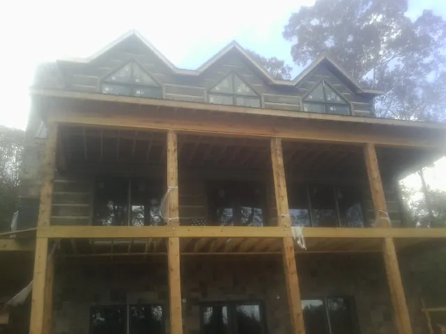 Dormers and porch framing on a large log home under construction — Roof Coating work by our crew in Liberty Hill
