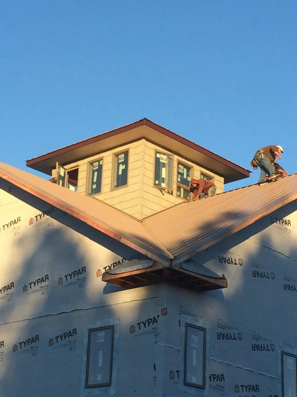 Roofers working around a rooftop cupola on a new metal roof at sunset — Roof Waterproofing in Liberty Hill by Roofing Brothers